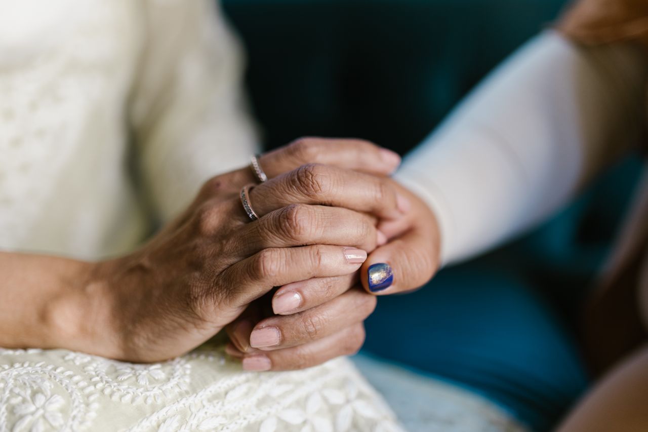 Two pairs of hands gently held together in comfort and support