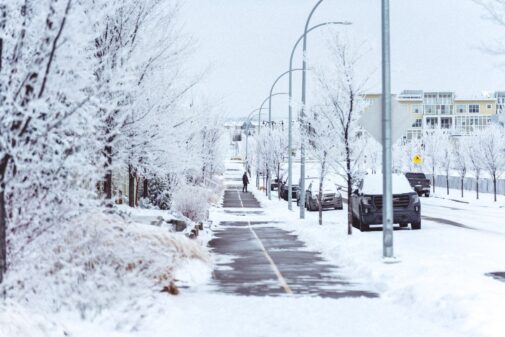 A snow-covered municipal street with a cleared sidewalk in winter